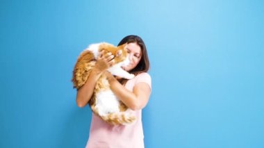 Büyük, yumuşak, beyaz ve kırmızı bir kedi tutan kadın.