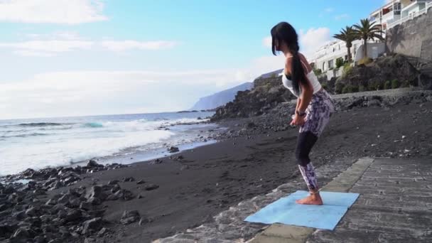 人生のバランス スポーツウェアのスリムスポーティな女性の完全な長さは 穏やかな朝 リアビューで海岸でヨガや瞑想を練習します 健康的なライフスタイルのコンセプト — ストック動画