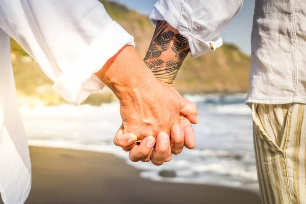 lifestyle with caucasian senior couple resting on beach, holding hands close up, happy in love romantic and relax time, tourism of elderly family pleople, leisure and activity travel after retirement