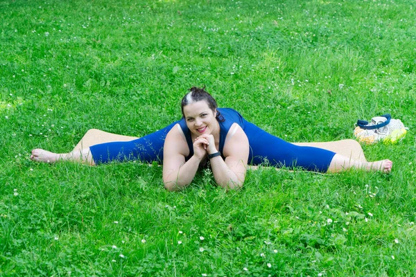Woman and sports, exercise for weight loss in the fresh air. Happy curvy 40s woman doing workout stretch routine outdoor at city park