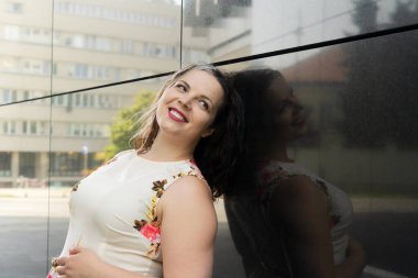 40 'lı yaşların portresi artı şehirde mutlu bir şekilde gülümseyen bir kadın.