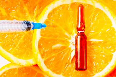 C vitamini, doğal yaşlanmayı önleyen kozmetik serumu ve portakal dilimlerinin üzerine şırınga.