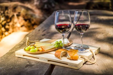 kırmızı şarap kadehleriyle piknik, güneş ışığıyla ekmek ve peynir