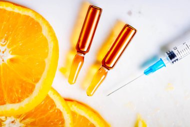 C vitamini, doğal yaşlanmayı önleyen kozmetik serumu ve meyve dilimli şırınga.