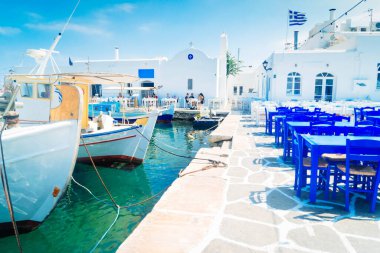 Naoussa village with mooring boats and cafe tables with sunshine