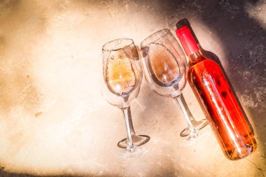 Pembe şarap bardaklarda ve şişelerde. Yakın çekim, üst manzara.