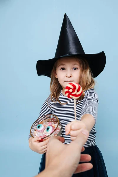 Holčička Čarodějnickém Klobouku Rozdává Lízátko Dělá Štěněčí Oči Oblečená Halloween — Stock fotografie