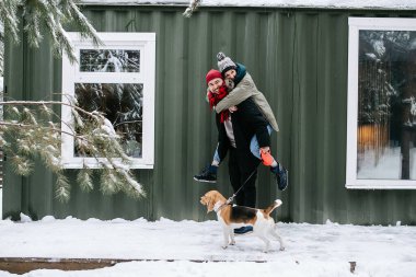 Fotoğrafa poz veren oyuncu bir çift, kadını sırtında taşıyan bir adam. Kışın kapalı kapılar. Örtülü çarşaf evinin önünde..