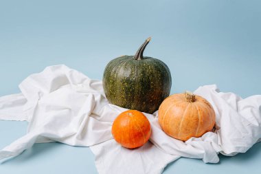 Beyaz bir kumaş parçasında balkabakları. Mavi arkaplan.