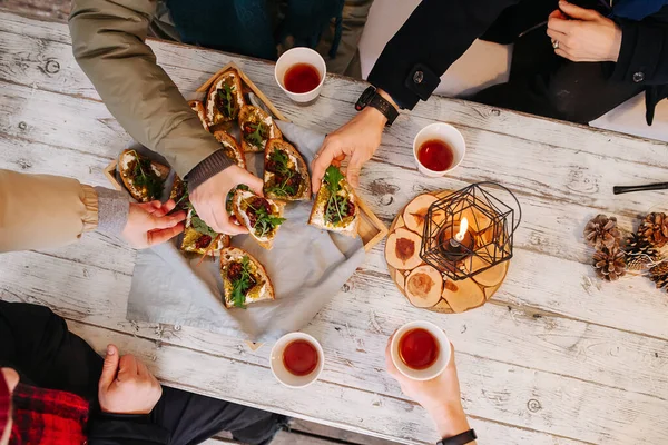 Widok na ludzi jedzących pyszne tosty bruschetta na drewnianym stole na świeżym powietrzu — Zdjęcie stockowe