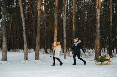 Kış parkında bir çocukla yürüyen çiftin yan görüntüsü.