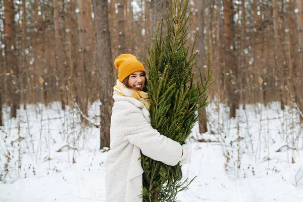 Усміхнена жінка в зимовому лісі обіймає ялинку . — стокове фото