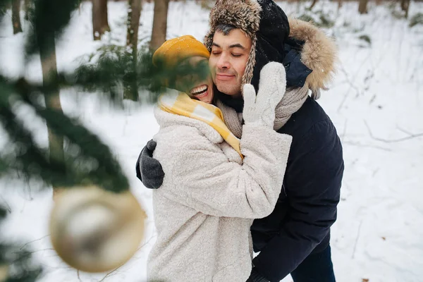 Люблячі пари взимку, вони обіймаються стоячи за ялинкою — стокове фото