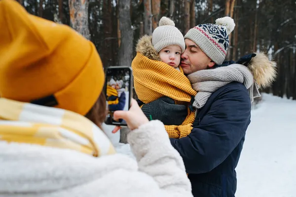 Сімейні свята. Мама знімає зимове фото батька з маленькою донькою — стокове фото