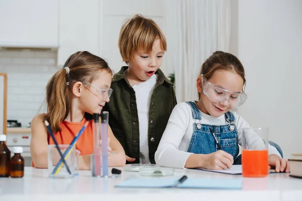 Щасливі маленькі діти роблять домашній науковий проект, дівчинка документує процес — стокове фото