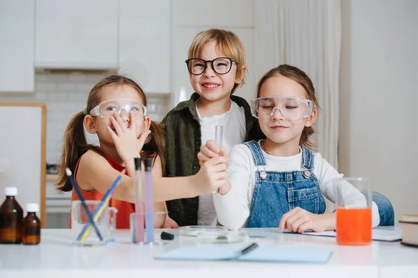 Живі маленькі діти роблять домашній науковий проект, проходячи колбу — стокове фото
