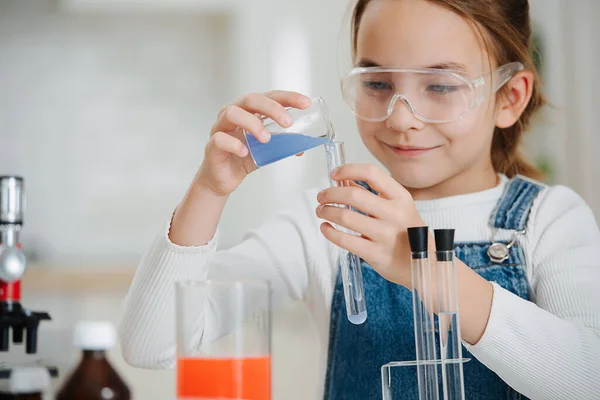 Sonriente chica haciendo el proyecto de ciencias caseras, vertiendo líquido en un frasco — Foto de Stock