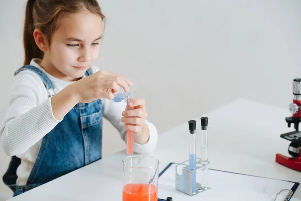 Paciente niña haciendo el proyecto de ciencias caseras, mezclando dos líquidos en un frasco — Foto de Stock