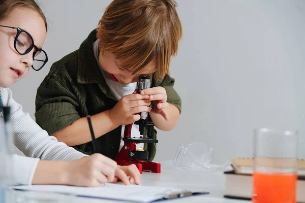 Chico Encogido Mirando Través Del Microscopio Chica Tomando Notas Lado — Foto de Stock