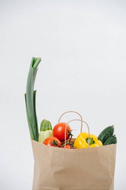 Grocery paper bag filled with colorful vegetables over white background. Eco friendly compostable products.