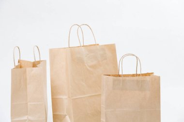 Three empty brown paper bags arranged in a composition over white background. Eco friendly compostable objects.