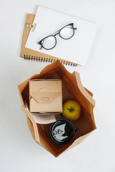 Ovanifrån Sammansättningen Lunch Papperspåse Och Glasögon Ett Anteckningsblock Äpple Kaffe — Stockfoto
