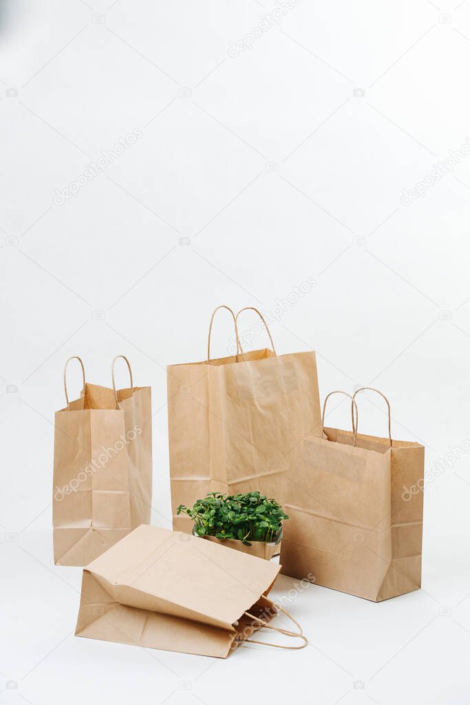 Empty brown paper bags and plant bed arranged in a composition over white background. One is laying flat on it's side. Eco friendly compostable objects.