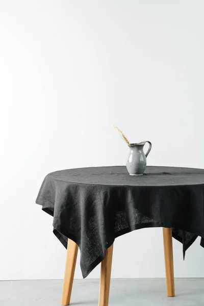Yuvarlak bir masada siyah kaba masa örtüsüyle mısır gevreği kulaklı bir sürahi. — Stok fotoğraf