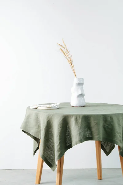 Yeşil bir masa örtüsü ve yuvarlak bir masada gevrek kulaklı moai şeklinde sürahi. — Stok fotoğraf