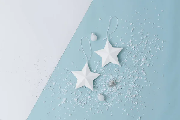 Dos estrellas blancas sobre un fondo blanco y azul salpicado de nieve artificial —  Fotos de Stock