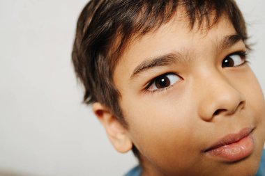 Beyaz arkaplanı kapatan Hintli bir çocuğun yüzü. Kameraya bakıyorum..