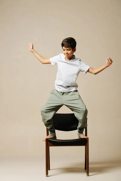 Щасливий Індійський Хлопчик Танцює Кріслі Рухаючи Руками Боках Згинаючи Коліна — стокове фото