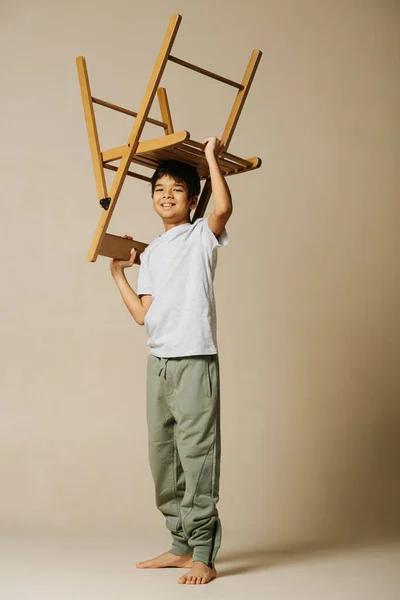 Usmívající Indiánský Chlapec Hrál Dřevěnou Skládací Židlí Béžové Místnosti Drží — Stock fotografie