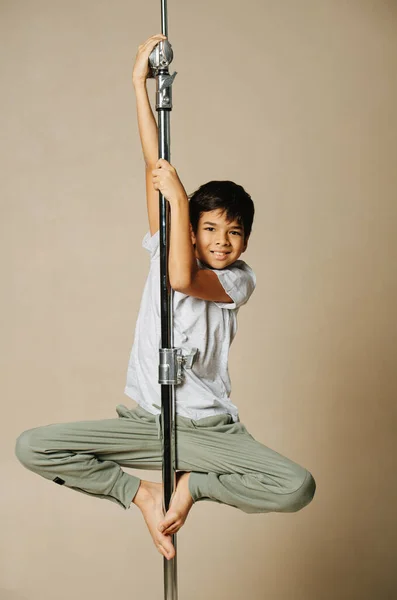 轻盈的印第安男孩挂在一根杆子上 用手和鞋底抓住 因为米色的背景他穿得很随便 — 图库照片