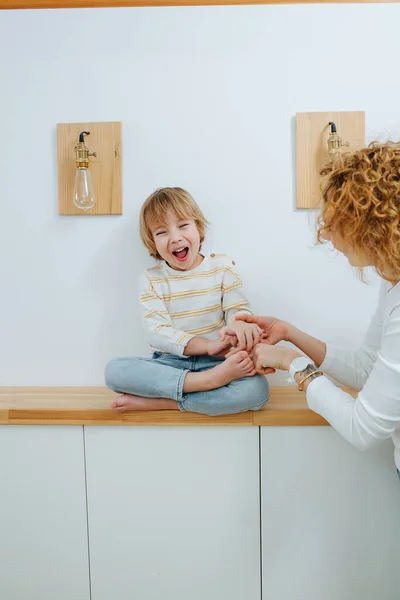 Niño Emocionado Haciéndole Cosquillas Madre Sentado Con Las Piernas Cruzadas —  Fotos de Stock