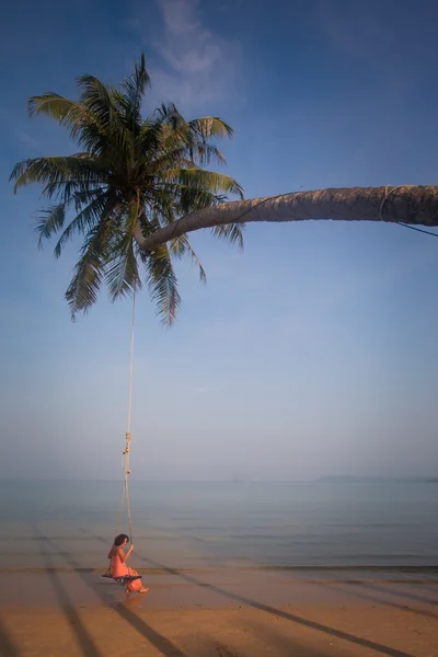 Schöne Mädchen auf einer Schaukel am Strand — Stockfoto