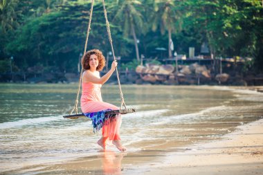 Sahilde bir salıncak üzerinde güzel kız