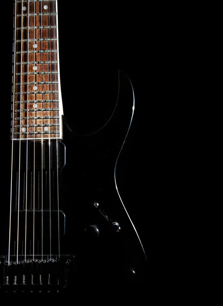 Black electric guitar with seven strings close up isolated on black background