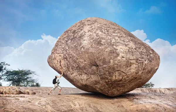 Homem empurrando uma grande pedra — Fotografia de Stock