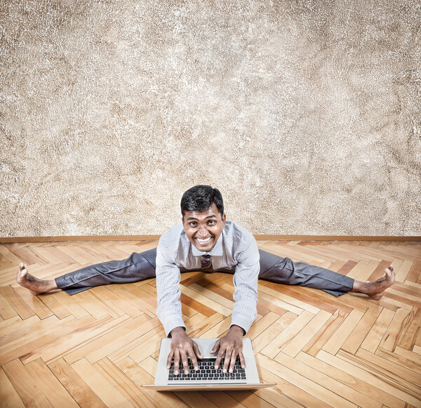 Indian man doing yoga with laptop