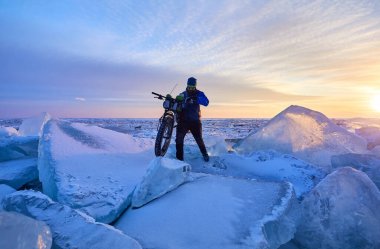 Kazakistan 'da gün batımında donmuş gölde motosikletli bir adam Kapchagay.