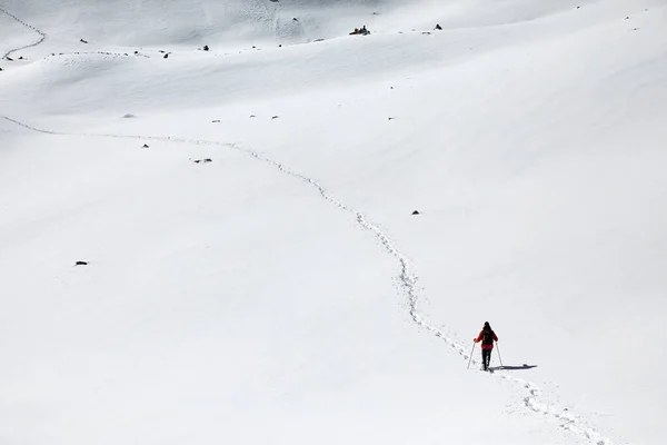 カザフスタンのアルマトイの足跡を持つ雪の丘の上を歩くリュックを持つ男 — ストック写真