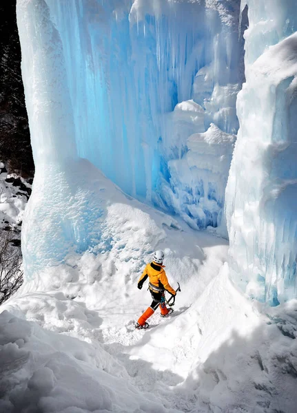 Žena Horolezec Oranžové Bundě Ledovou Sekerou Chůze Zamrzlého Vodopádu Horách — Stock fotografie