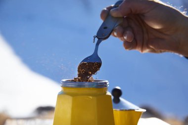 Sarı Moka moka çaydanlığından kış dağlarında açık havada kahve yapan bir adam. Kamp yapmak için eski tarz kahve.