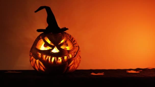 Halloween pumpkin with black hat glowing inside at night — Stockvideo