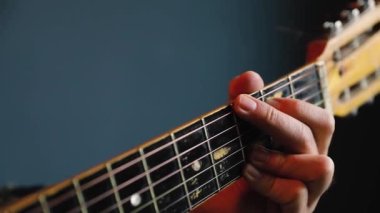 Adam mavi duvarda akustik gitar çalıyor.