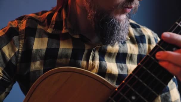 Man spelar akustisk gitarr på blå vägg — Stockvideo