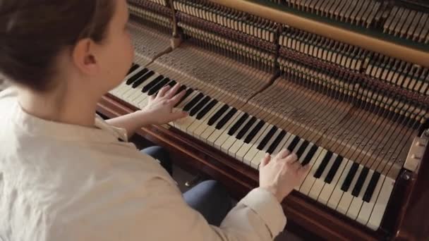 Женщина играет на открытом винтажном деревянном пианино — стоковое видео