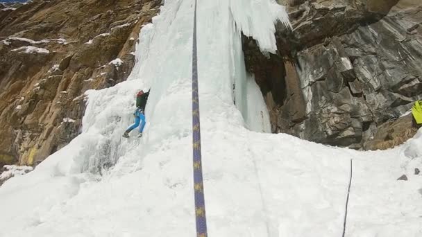 Homem escalando cascata de gelo com corda e machado de gelo — Vídeo de Stock