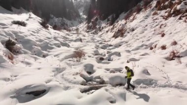 Yürüyüşçü güzel kış dağlarında nehri geçiyor.